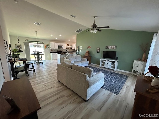 living area with vaulted ceiling, light wood-type flooring, and visible vents