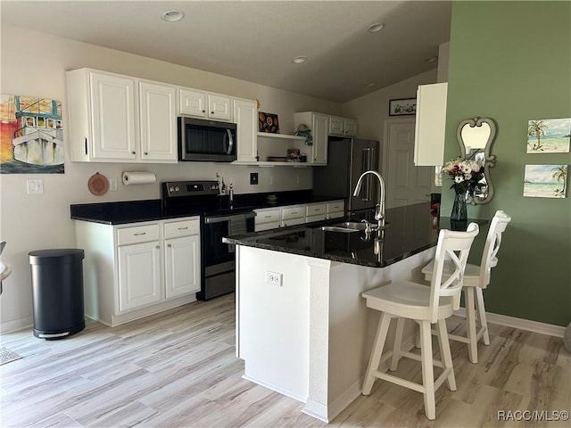 kitchen featuring stainless steel appliances, light wood-style floors, a peninsula, and white cabinets