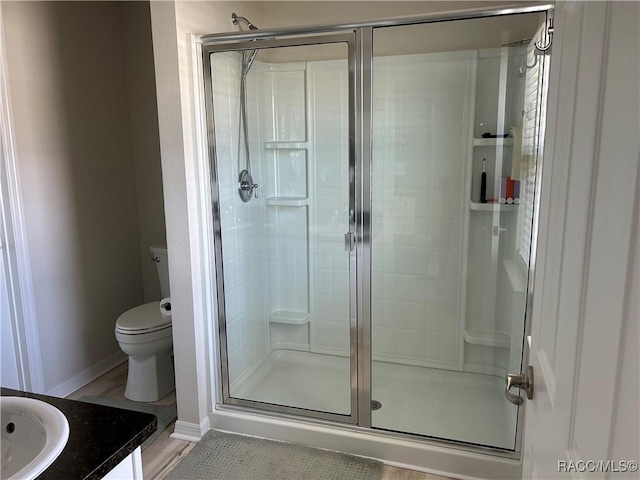 bathroom with a shower stall, baseboards, vanity, and toilet