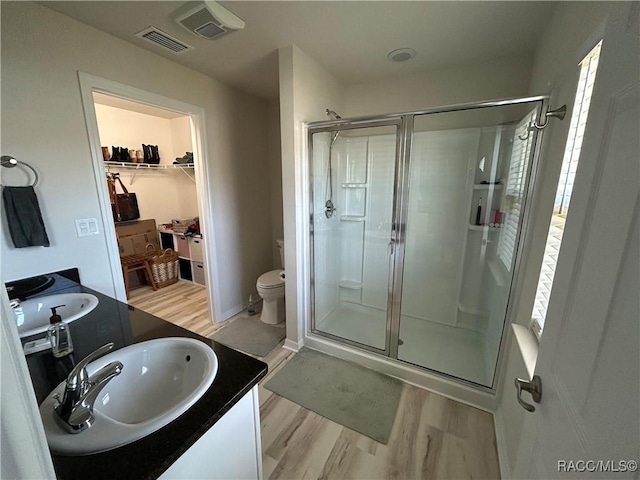 full bathroom featuring wood finished floors, vanity, visible vents, a spacious closet, and a stall shower