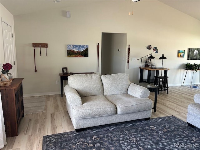 living room featuring light wood-style floors, baseboards, and high vaulted ceiling