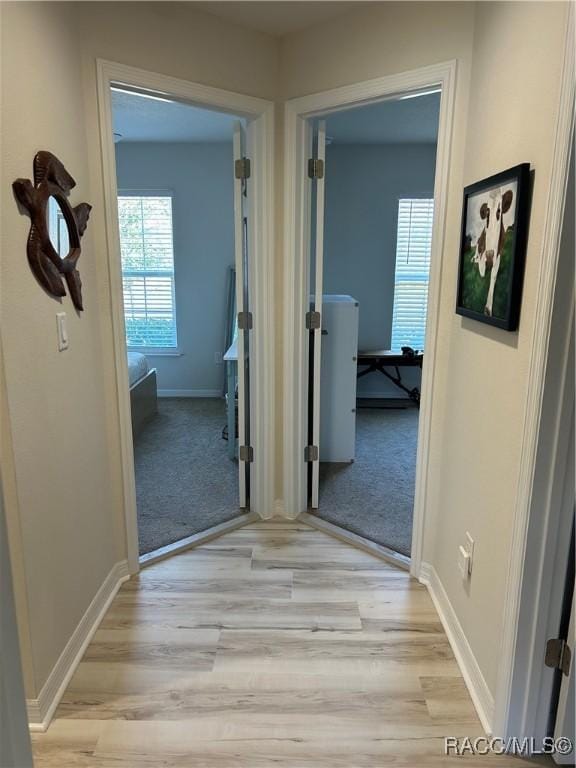 corridor featuring baseboards and light wood-style floors