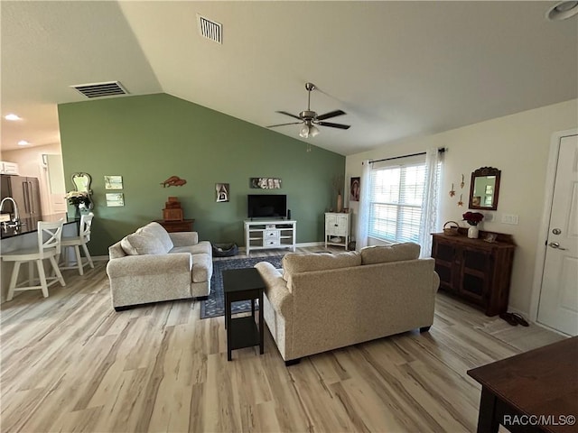 living room with lofted ceiling, visible vents, ceiling fan, and light wood finished floors