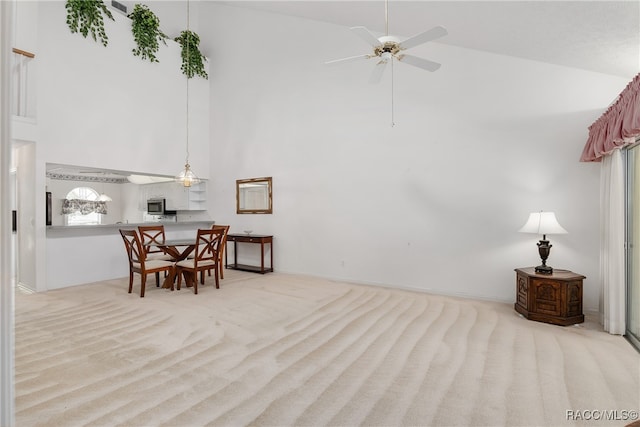 carpeted dining area with ceiling fan and high vaulted ceiling