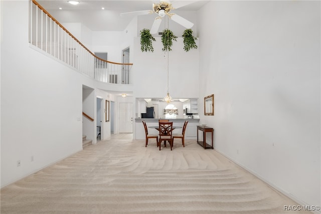 corridor featuring a towering ceiling and light colored carpet