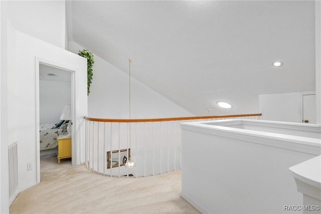 corridor with light colored carpet and lofted ceiling