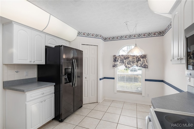 kitchen with white cabinetry, hanging light fixtures, black fridge, decorative backsplash, and light tile patterned flooring