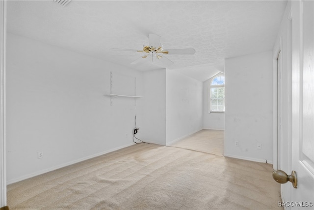 spare room featuring a textured ceiling, ceiling fan, light carpet, and vaulted ceiling