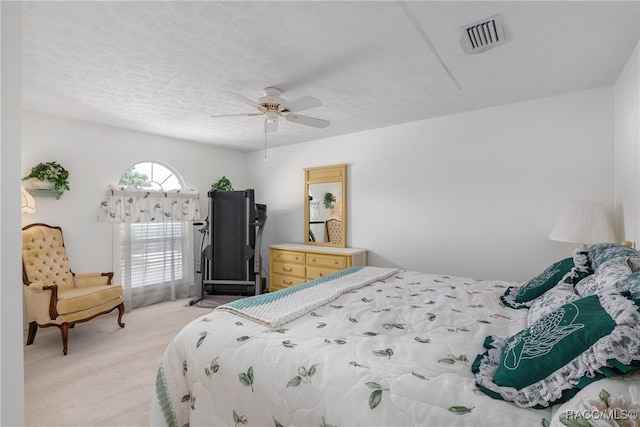 bedroom with ceiling fan, light colored carpet, and a textured ceiling