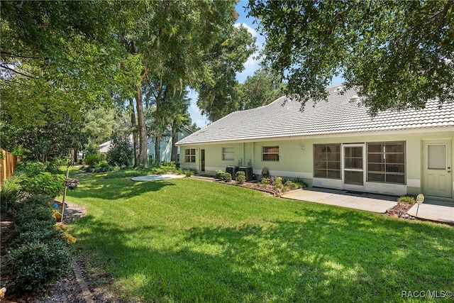 back of house featuring central AC unit and a lawn