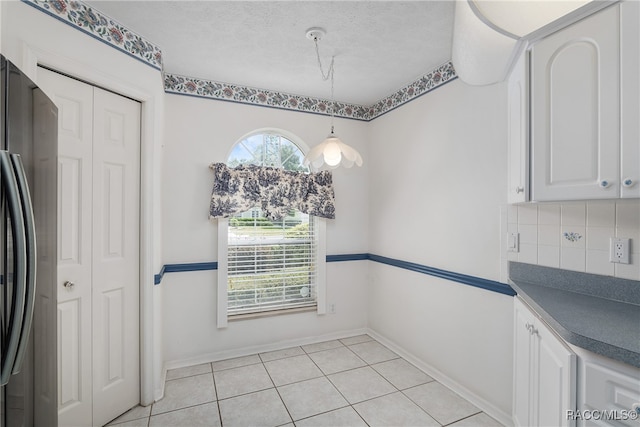 unfurnished dining area featuring light tile patterned flooring and a textured ceiling