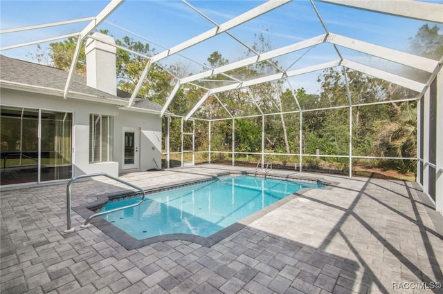 view of swimming pool featuring glass enclosure and a patio