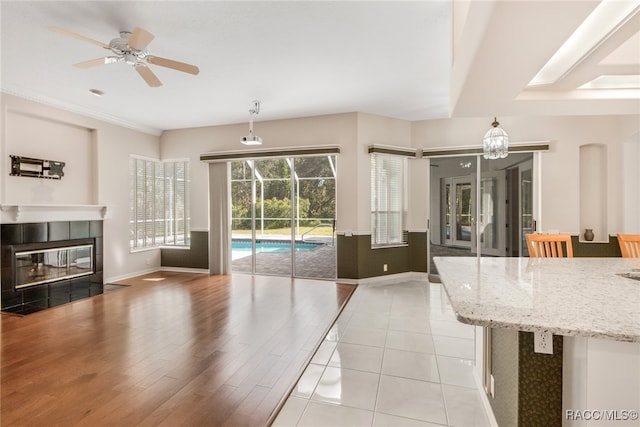 living room with ceiling fan, light wood-type flooring, and a tile fireplace