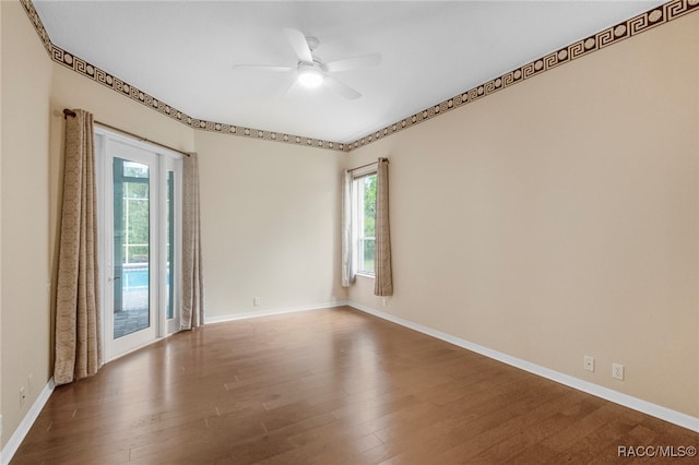 empty room featuring ceiling fan, plenty of natural light, and hardwood / wood-style flooring