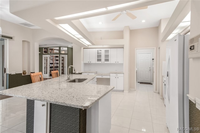 kitchen featuring white cabinets, light tile patterned flooring, a kitchen island with sink, and sink