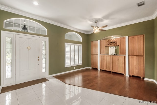 foyer entrance with crown molding, ceiling fan, and light wood-type flooring