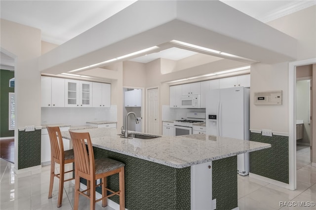 kitchen with a large island with sink, sink, white cabinets, and white appliances