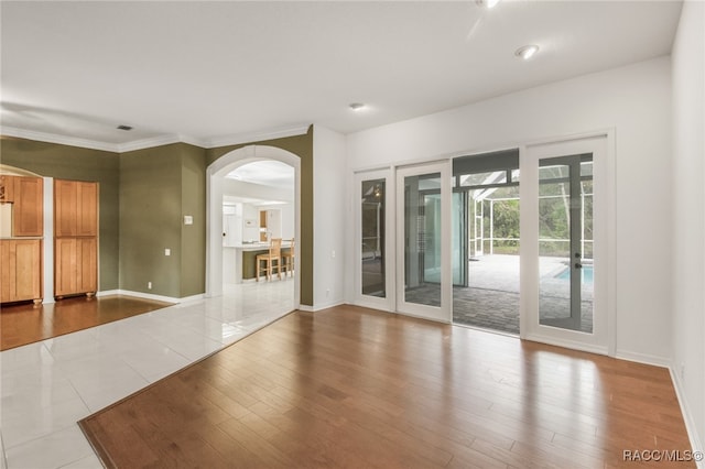 empty room featuring wood-type flooring, crown molding, and french doors