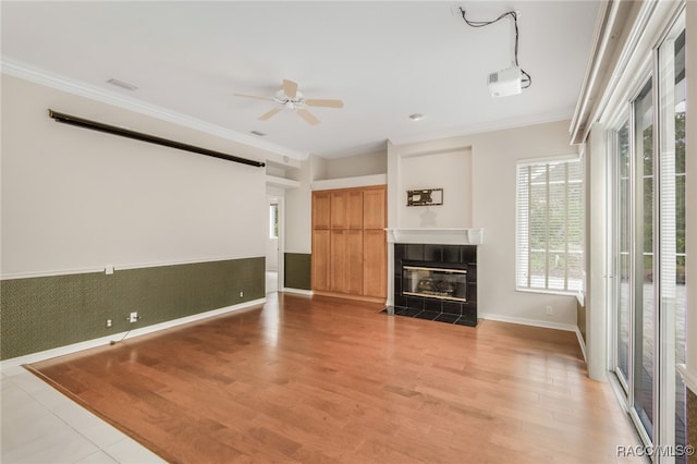 unfurnished living room featuring ceiling fan, light hardwood / wood-style floors, ornamental molding, and a fireplace