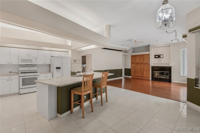 kitchen featuring light hardwood / wood-style flooring, an island with sink, pendant lighting, white appliances, and white cabinets