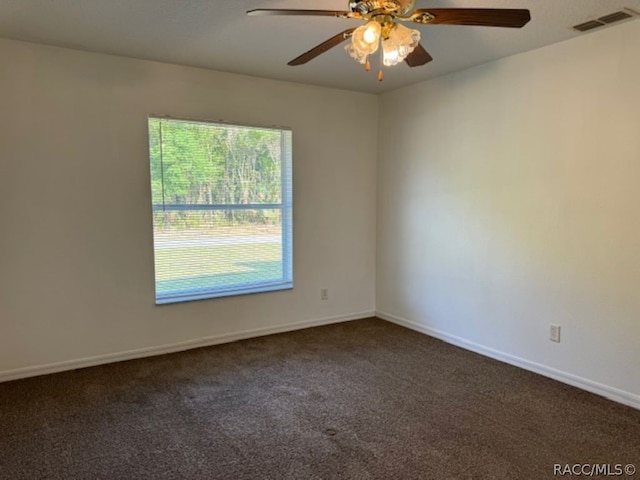 spare room featuring ceiling fan and dark carpet