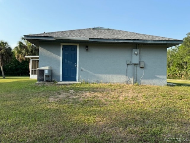 back of property featuring a yard and central AC