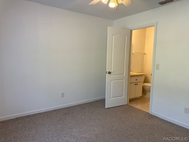 unfurnished bedroom with ceiling fan, light colored carpet, and ensuite bath