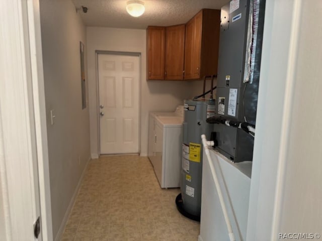 washroom featuring washing machine and dryer, water heater, cabinets, and a textured ceiling