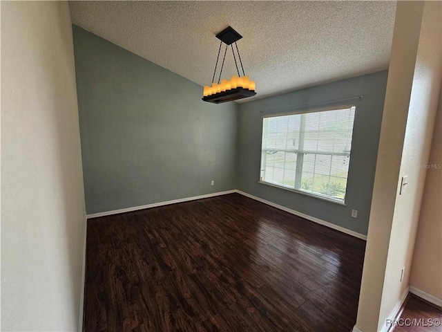 empty room with dark wood-style floors, a textured ceiling, and baseboards