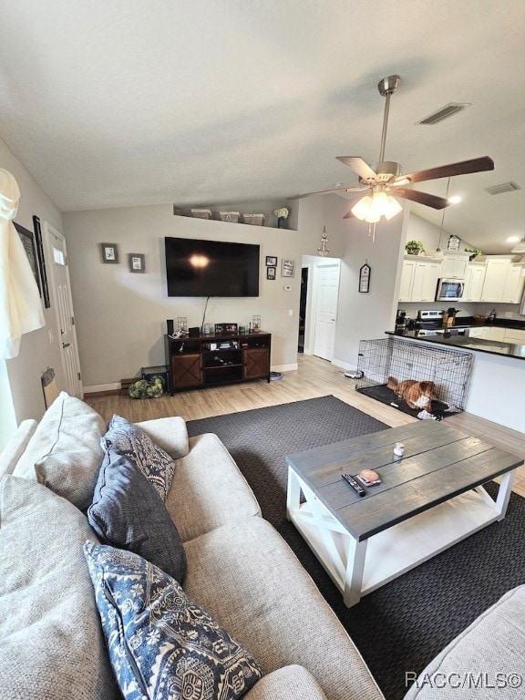 living room featuring ceiling fan, lofted ceiling, and light hardwood / wood-style flooring