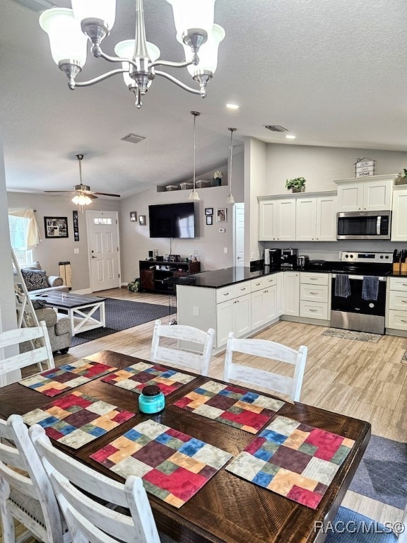 dining room featuring ceiling fan with notable chandelier, light hardwood / wood-style flooring, and vaulted ceiling