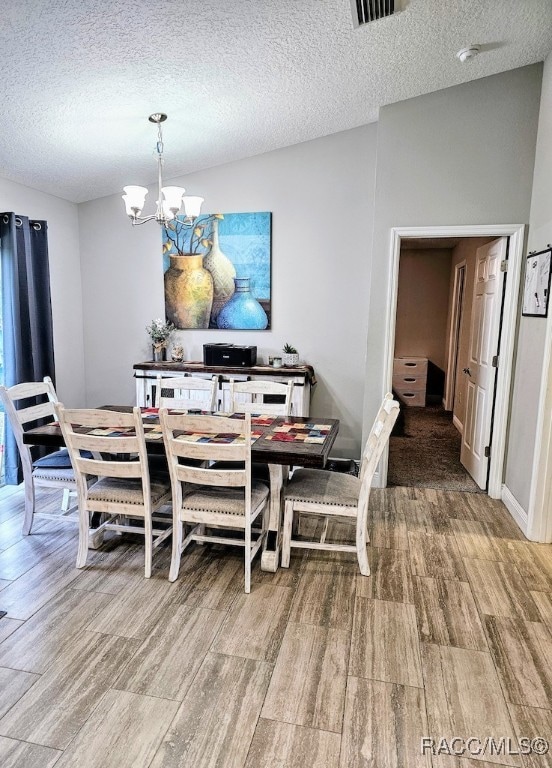 dining room with hardwood / wood-style floors, a textured ceiling, and an inviting chandelier