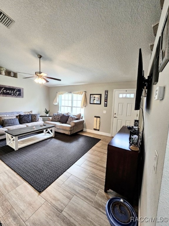 living room featuring ceiling fan, light hardwood / wood-style floors, and a textured ceiling