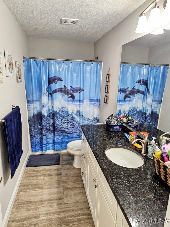 bathroom featuring a shower with curtain, vanity, toilet, and a textured ceiling