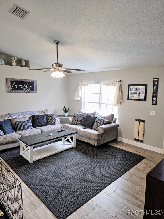 living room with a textured ceiling, light wood-type flooring, and ceiling fan