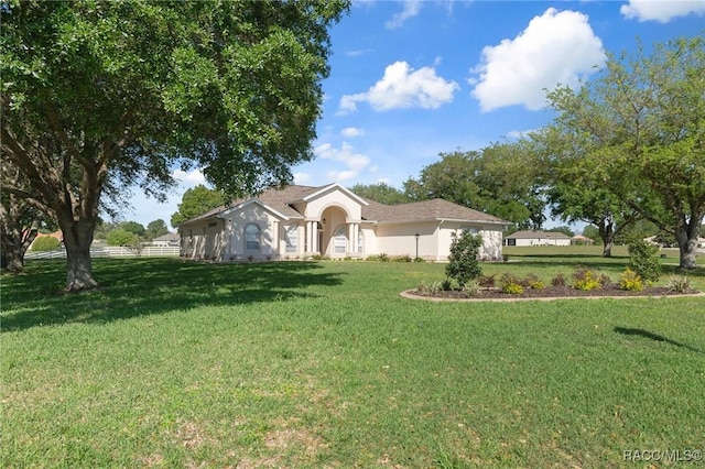 ranch-style house with a front lawn, fence, and stucco siding