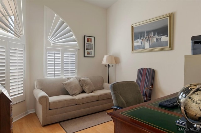 home office featuring baseboards, light wood-type flooring, and a healthy amount of sunlight