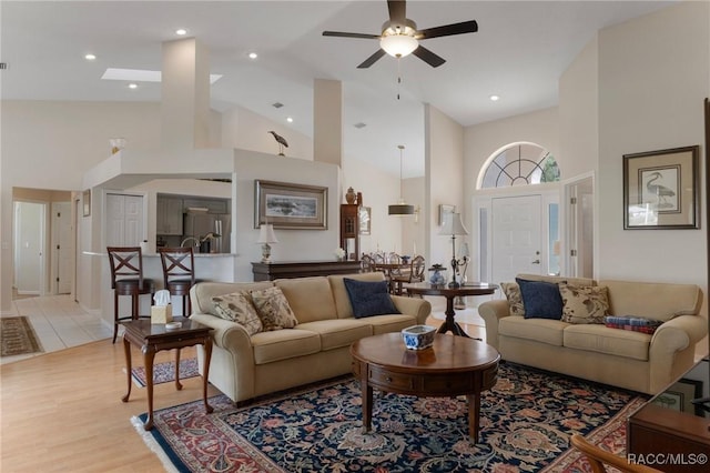 living room featuring high vaulted ceiling, light wood-style flooring, and ceiling fan