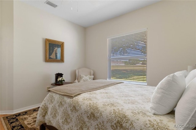 bedroom with ceiling fan, visible vents, baseboards, and wood finished floors