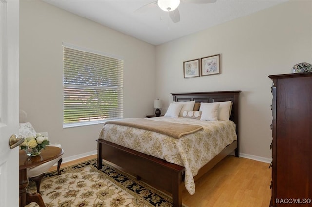 bedroom featuring light wood-style flooring, baseboards, and a ceiling fan