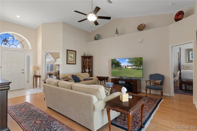 living room featuring high vaulted ceiling, light wood-type flooring, and a ceiling fan