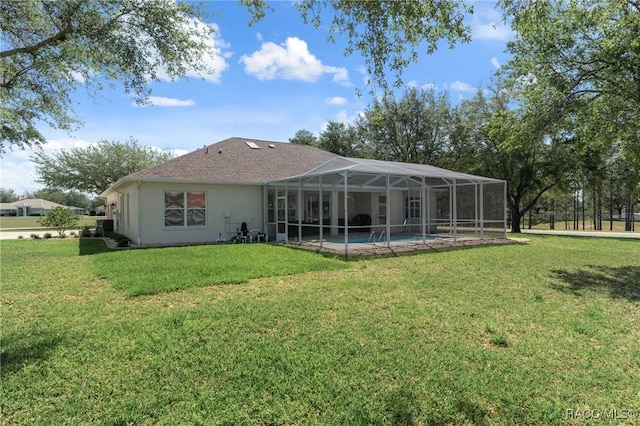 rear view of property featuring a yard, an outdoor pool, stucco siding, and a lanai