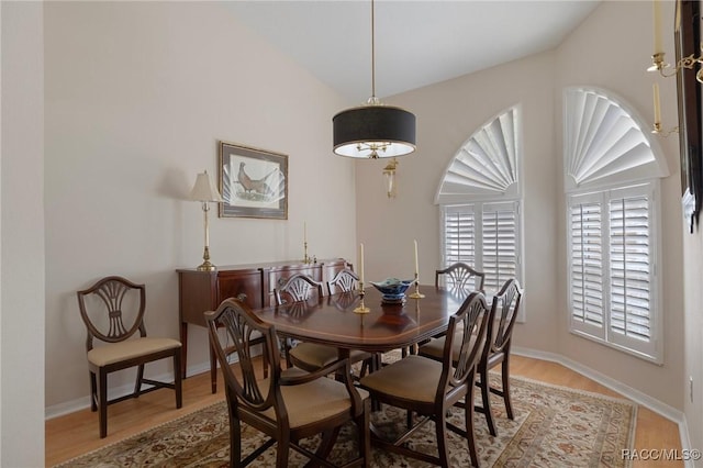 dining space featuring baseboards, vaulted ceiling, and wood finished floors