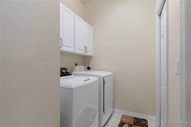 washroom featuring cabinet space, light tile patterned floors, washer and clothes dryer, and baseboards
