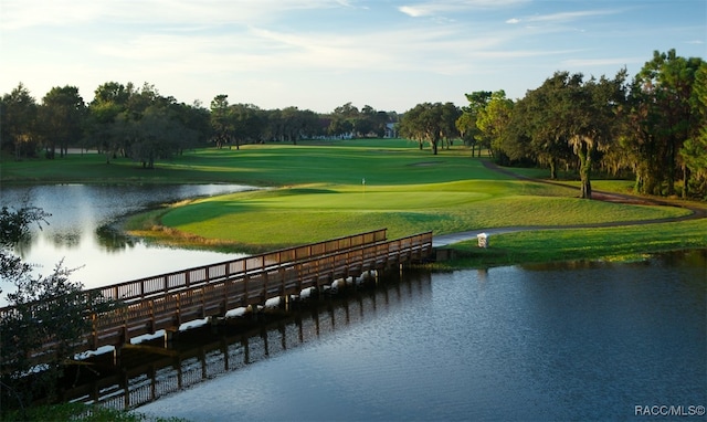 view of property's community with a water view, a yard, and golf course view