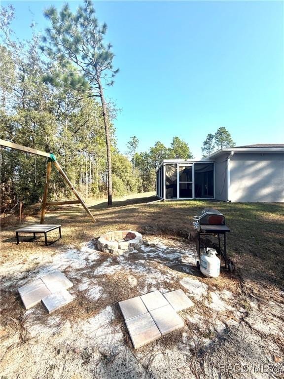 view of yard featuring a fire pit, a sunroom, and a playground