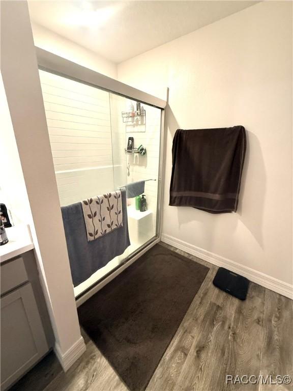 bathroom featuring hardwood / wood-style flooring, vanity, and a shower with door