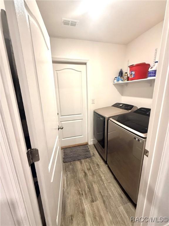 laundry area with washing machine and dryer and light wood-type flooring