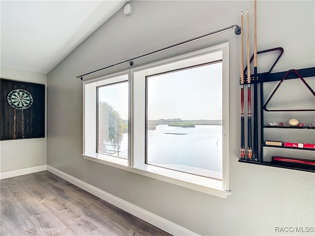 empty room with a water view, baseboards, wood finished floors, and lofted ceiling