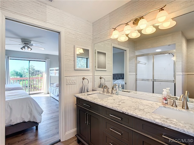 bathroom featuring wood-type flooring, vanity, a shower with door, wood walls, and ceiling fan